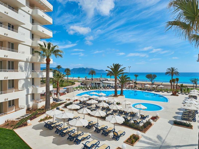 Hotel s bazénem a výhledem na moře, lehátka a slunečníky na terase