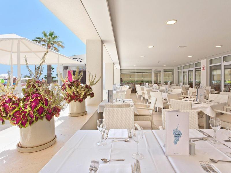 Světá, elegantní terasa restaurace s bílými stoly a květinovými aranžmá.