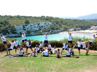 Groupe de personnes formant une pyramide acrobatique sur une colline herbeuse près de la côte.