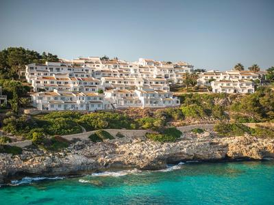 Witte gebouwen op een heuvel met uitzicht op helderblauwe zee en rotsachtige kust.