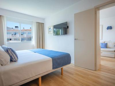 Moderne hotelkamer met tweepersoonsbed, tv en uitzicht op een woonkamer.