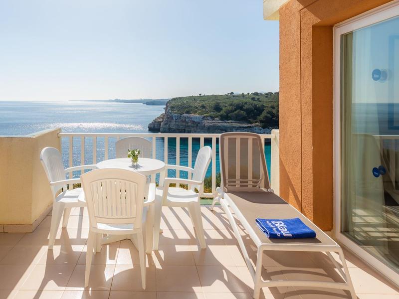 Balkon met witte stoelen en tafel met uitzicht op zee op een zonnige dag.