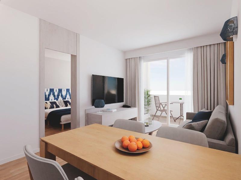 Moderne woonkamer met eettafel, bank, tv en balkon met uitzicht op zee.