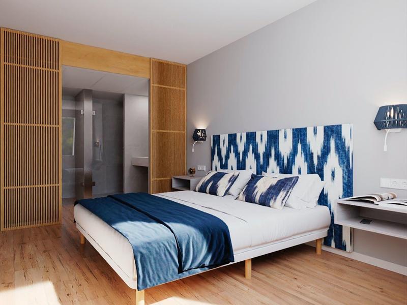 Moderne hotelkamer met tweepersoonsbed, blauw-wit hoofdeinde en houten vloer.