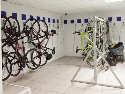 Locale per biciclette con diverse bici appese al muro e un rastrelliera per biciclette.