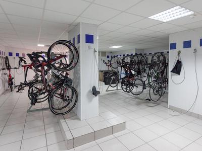Garage per biciclette moderno con pareti piastrellate bianche e più biciclette su scaffali.