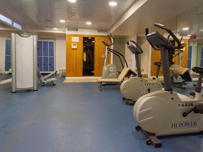 Palestra con diverse cyclette e attrezzi da ginnastica su pavimento blu.