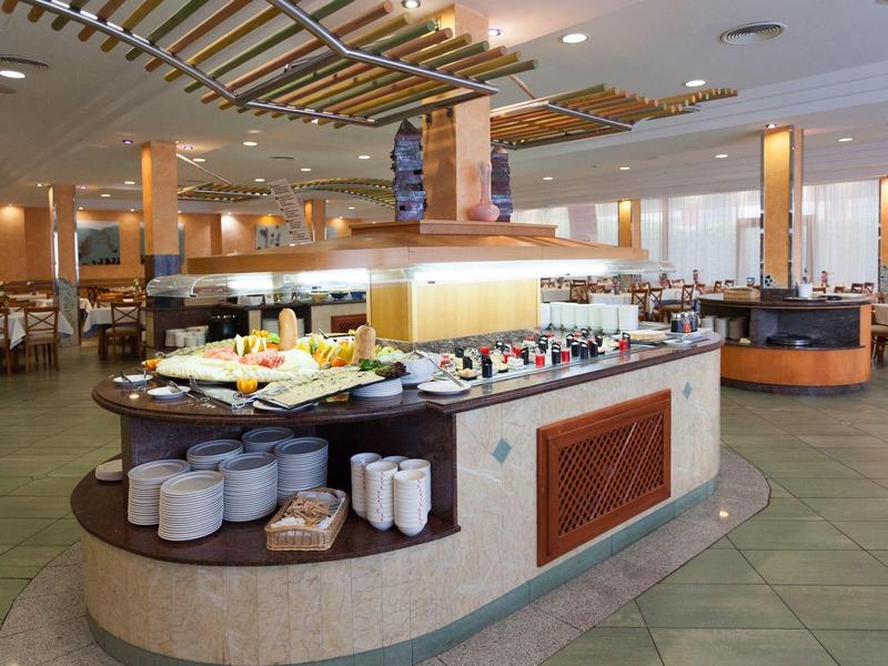 Strefa bufetu w jasnej restauracji hotelowej z różnymi potrawami i zastawą stołową.