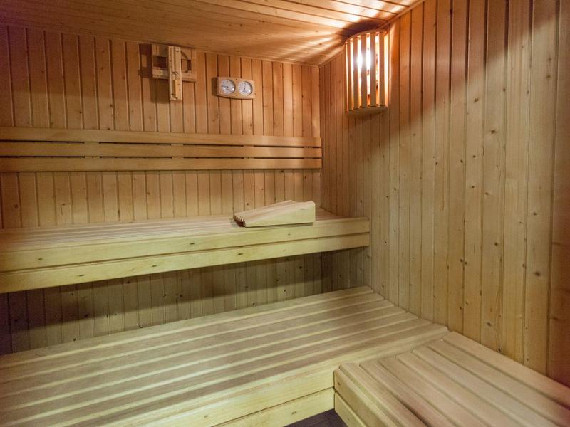 Jasna sauna z drewnianymi ścianami, drewnianymi ławkami i ręcznikiem jako wyposażeniem.