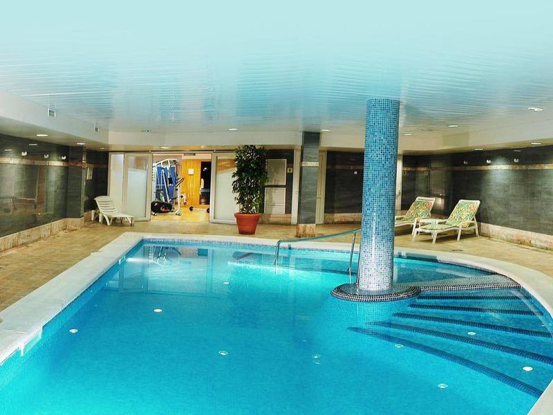 Nowoczesny kryty basen z spokojną wodą, zielonymi roślinami i wygodnymi leżakami