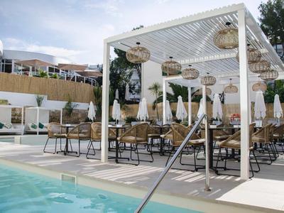 Nowoczesny basen z białymi pergolami, krzesłami i parasolami pod niebieskim niebem.