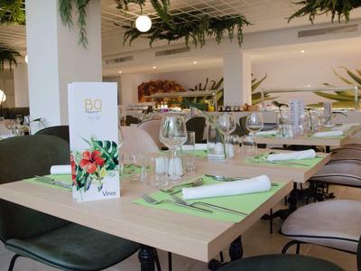 Elegancka restauracja z nowoczesnym wnętrzem i zastawionymi stołami z zielonymi sztućcami.