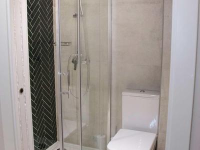 Kompaktowy nowoczesny kąt łazienki z kabiną prysznicową i toaletą w neutralnych kolorach.