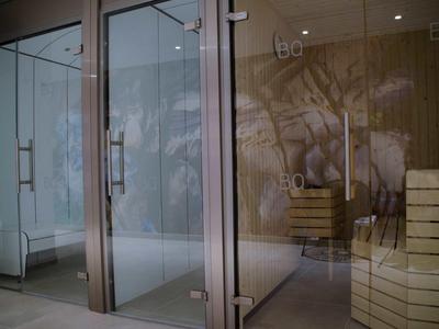 Nowoczesna strefa wellness z szklanymi kabinami prysznicowymi i drewnianymi ławkami w spa.