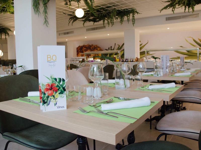 Elegancka restauracja z nowoczesnym wnętrzem i zastawionymi stołami z zielonymi sztućcami.