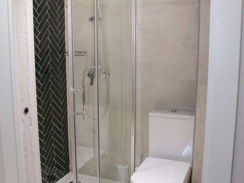 Kompaktowy nowoczesny kąt łazienki z kabiną prysznicową i toaletą w neutralnych kolorach.