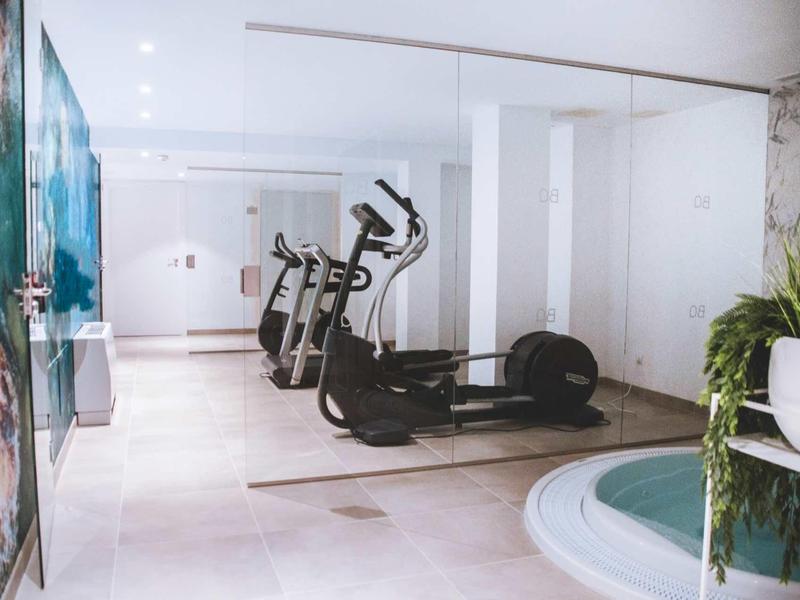 Nowoczesna siłownia z bieżnią i jacuzzi w jasnej części hotelu.