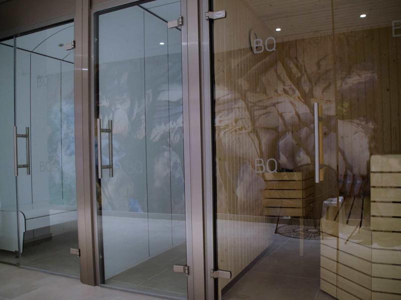 Nowoczesna strefa wellness z szklanymi kabinami prysznicowymi i drewnianymi ławkami w spa.