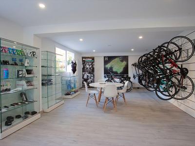 Modern bike and accessory shop with wall-mounted bikes and table with chairs in bright rooms.