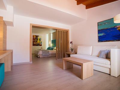 Camera d'hotel dal design moderno con divano bianco e vista sulla camera da letto.