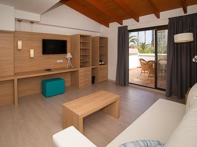 Soggiorno luminoso con soffitto in legno, scrivania, TV e accesso alla terrazza con mobili da giardino.