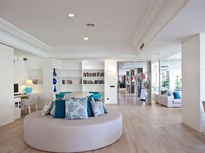 Lobby dell'hotel luminosa e moderna con divano circolare, poltrone e reception sullo sfondo.