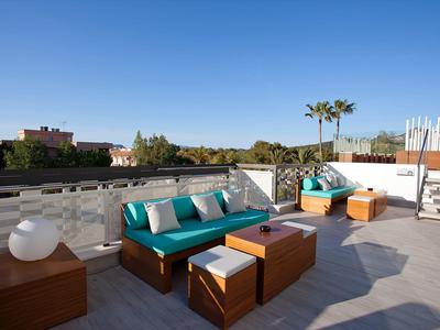 Terrazza con zona salotto moderna e cuscini blu sotto un cielo limpido