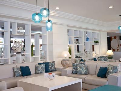 Area lounge di un hotel moderno con divani bianchi, accenti blu e illuminazione elegante.