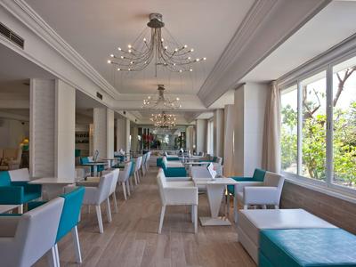 Sala da pranzo moderna e luminosa con sedute turchesi e grandi finestre con vista sul verde.