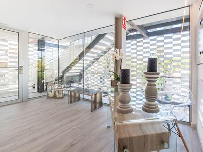 Camera d'hotel moderna con pareti in vetro, pavimenti in legno chiaro e oggetti decorativi su un comò.