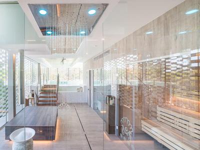 Area spa moderna con piscina riscaldata, sauna e pareti in vetro luminose.