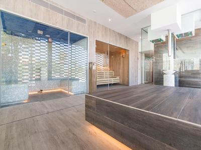 Area spa moderna con pavimento in legno, sauna e pareti in vetro.