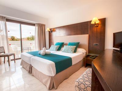 Camera d'albergo luminosa con letto grande, balcone e arredamento moderno.