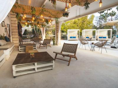 Area lounge moderna con mobili in legno e pallet, piante e posti a sedere all'aperto.