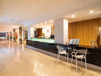 Una luminosa hall dell'hotel con un grande banco della reception e due sedie al bancone.