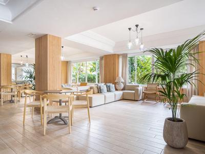 Area lounge d'hotel luminosa e moderna con piante e mobili in legno.