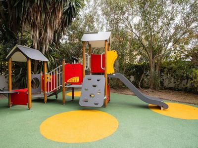 Area giochi colorata con scivolo e parete da arrampicata davanti agli alberi.