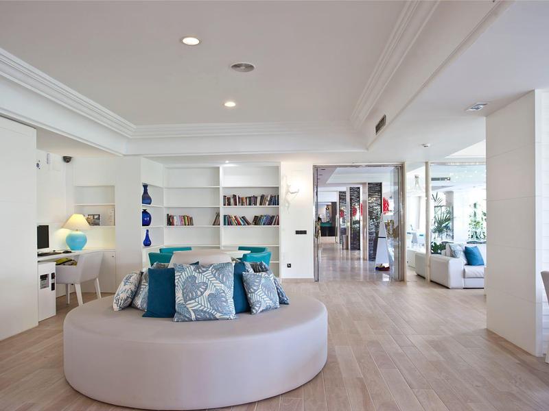 Lobby dell'hotel luminosa e moderna con divano circolare, poltrone e reception sullo sfondo.