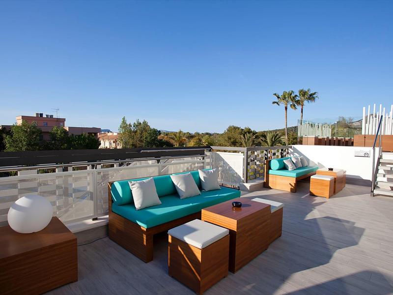 Terrazza con zona salotto moderna e cuscini blu sotto un cielo limpido