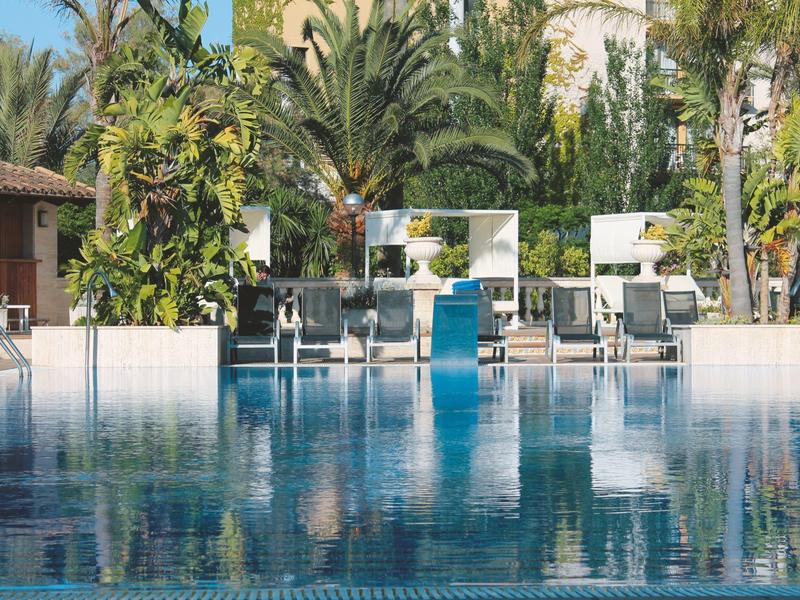 Grande piscina con lettini e palme sullo sfondo in un resort alberghiero.