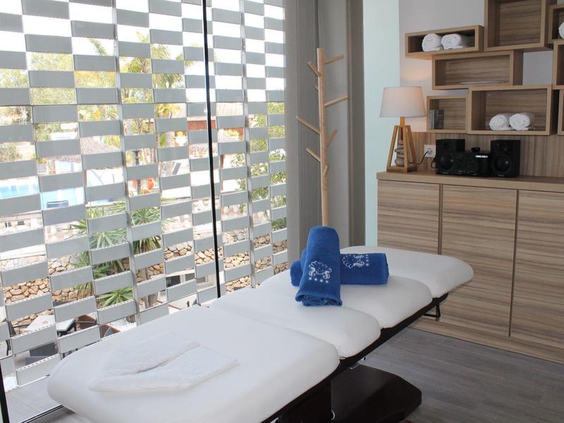 Luminoso spazio benessere con lettino da massaggio, asciugamani blu e scaffali moderni in legno