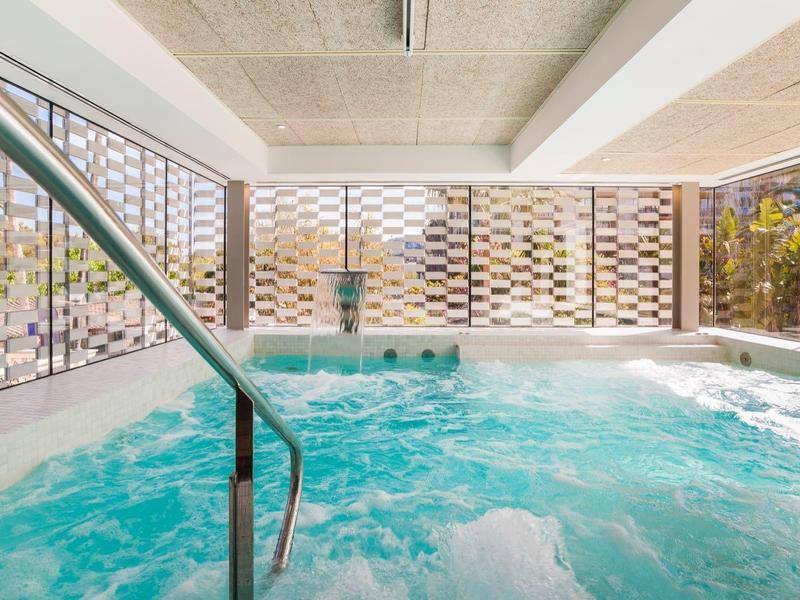 Vasca idromassaggio interna con acqua frizzante e illuminazione artificiale in un hotel moderno.