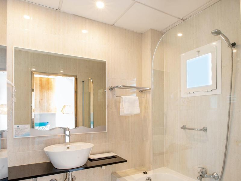 Bagno luminoso con lavabo, specchio, portasciugamani e doccia con finestra.