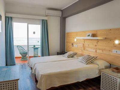 Double room with two single beds, wooden wall, side nightstands, and balcony with seating