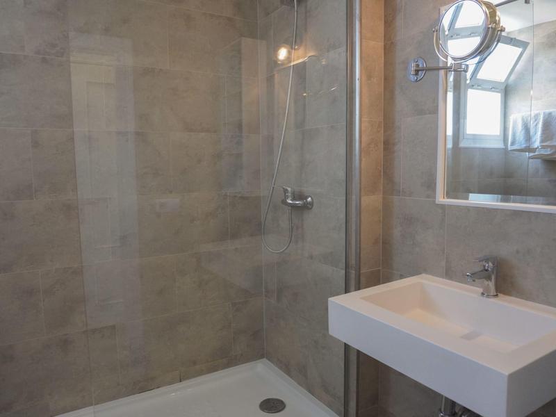 Modern bathroom with walk-in shower, gray stone wall tiles, and small rectangular sink