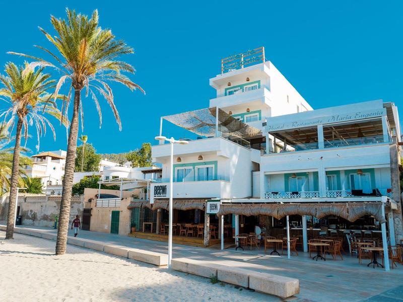 Modern multi-story hotel building with palm trees and clear sky at the beach.