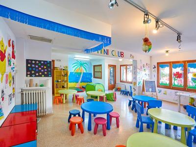 Bunte Kinderspielecke mit Tischen, Stühlen und Wanddekoration in einem Hotel.