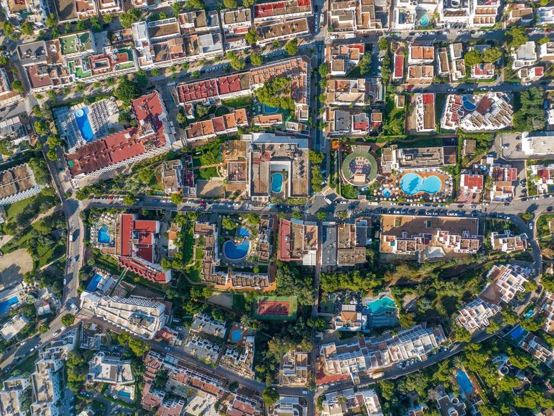 Aerial view of a densely built city with several swimming pools and abundant greenery.