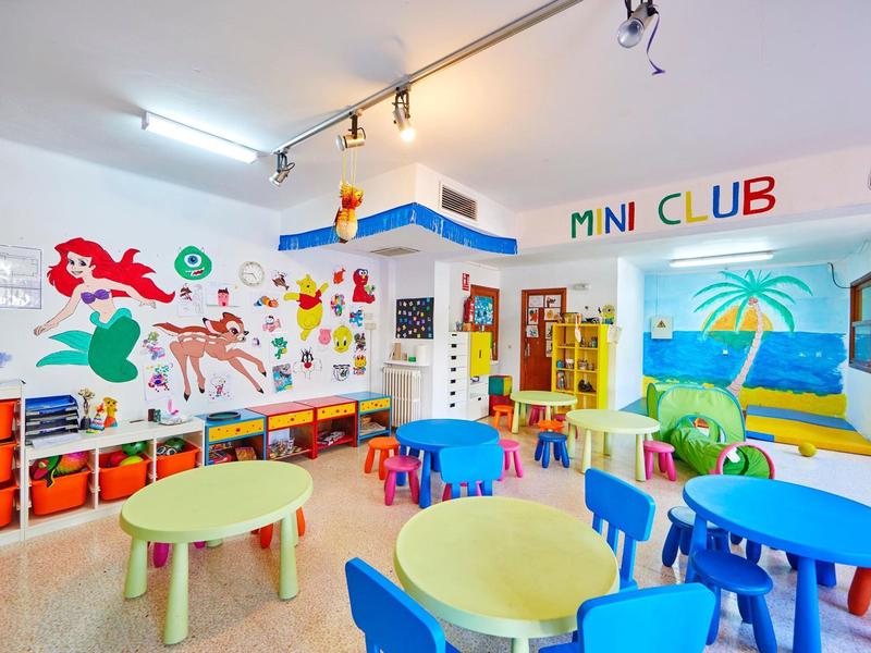 Colorful kids' playroom with small tables, chairs, and wall decorations for Mini Club.