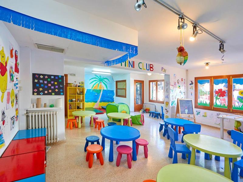 Children's area with colorful tables, chairs, and wall decorations in a bright room.